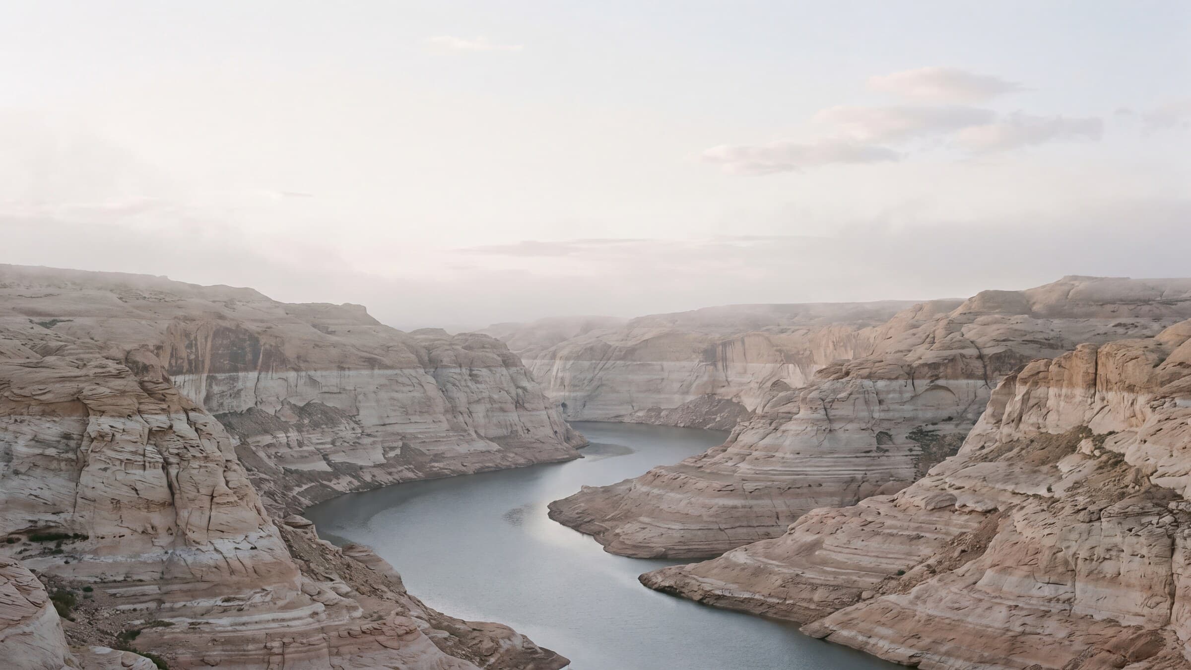 Blue reservoir water between layered desert cliffs